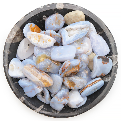 Pierres naturelles de calcédoine bleue dans un bol en marbre noir, pierre de l'apaisement, de confiance et d'expression de soi