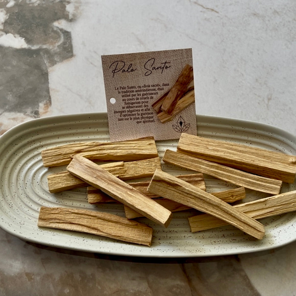 Batônnets de Palo Santo disposés dans un plat en céramique avec étiquette explicative