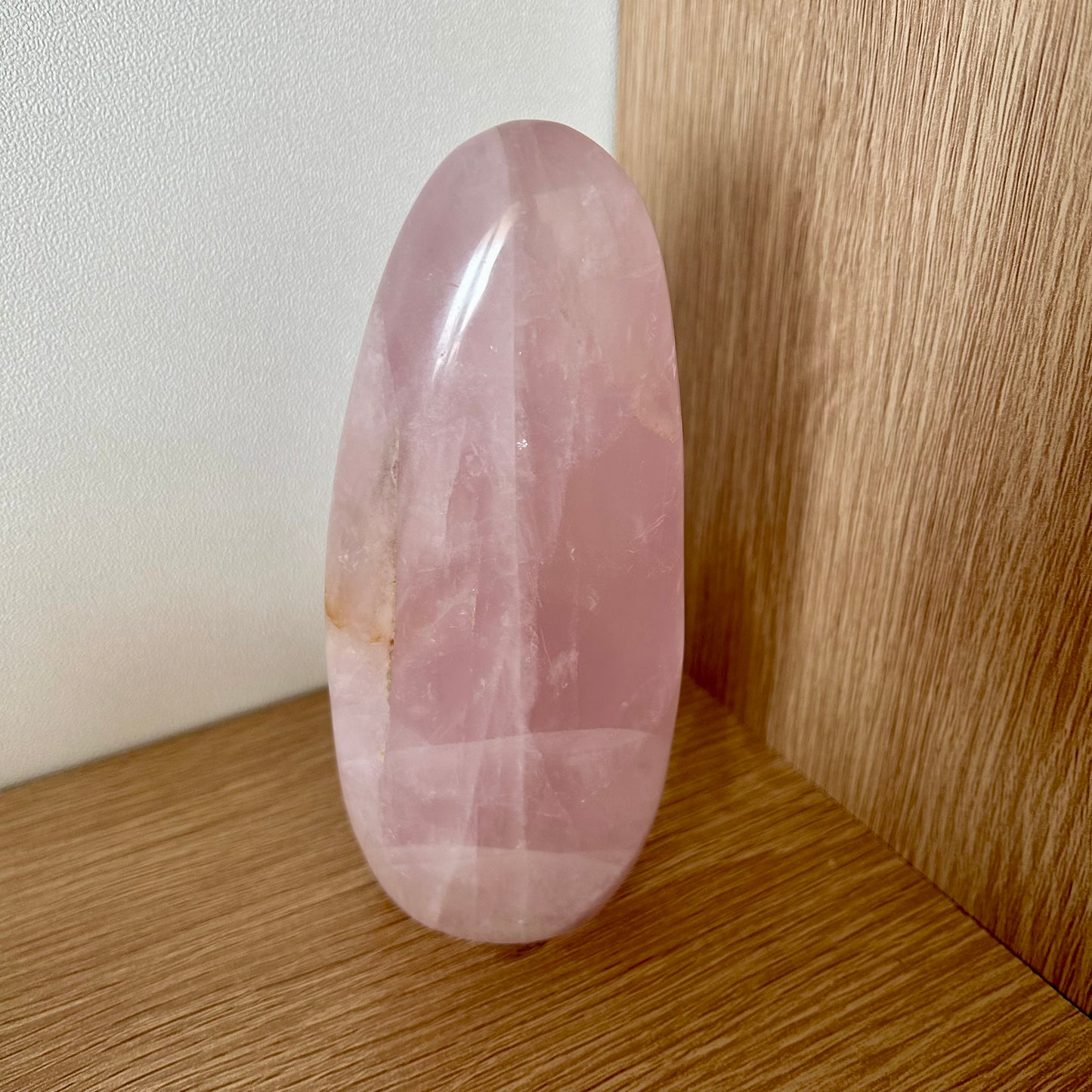 Pierre naturelle de quartz rose forme libre posée sur une étagère en bois