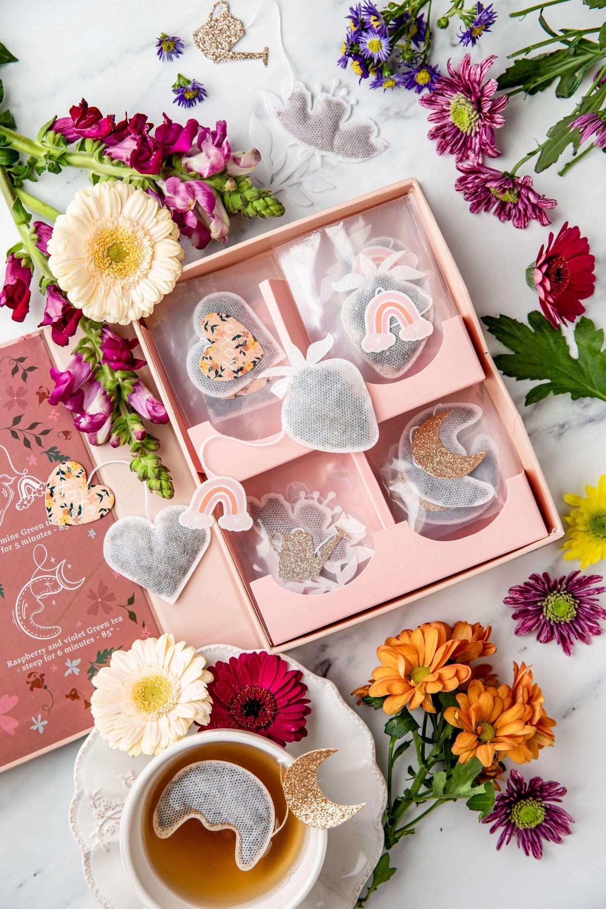 Intérieur du coffret rose de thés et d'infusions bio, 20 sachets en mousseline avec des formes différentes de fraise, fleur, lune et coeur, décor de fleurs