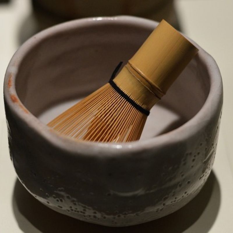Fouet à matcha chasen dans un bol gris en céramique, ambiance zen
