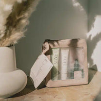 Trousse découverte MIYÉ et ses trois soins iconiques, posée sur une table en marbre avec vase en arrière plan