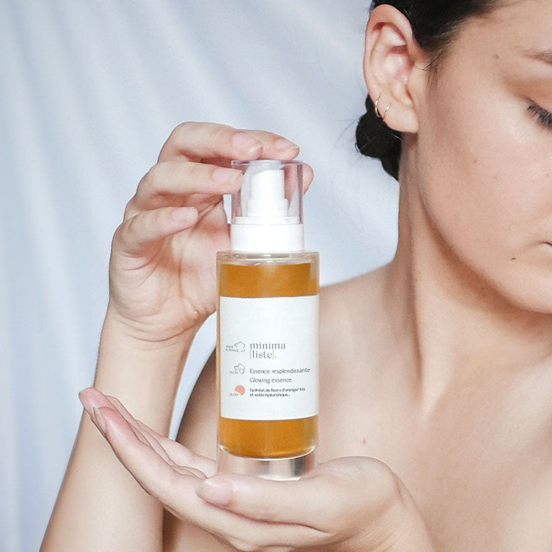 Femme tenant un flacon d'Essence resplendissante Minimaliste