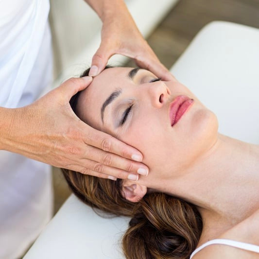 Femme pratiquant un soin énergétique lahochi sur la tête d'une cliente