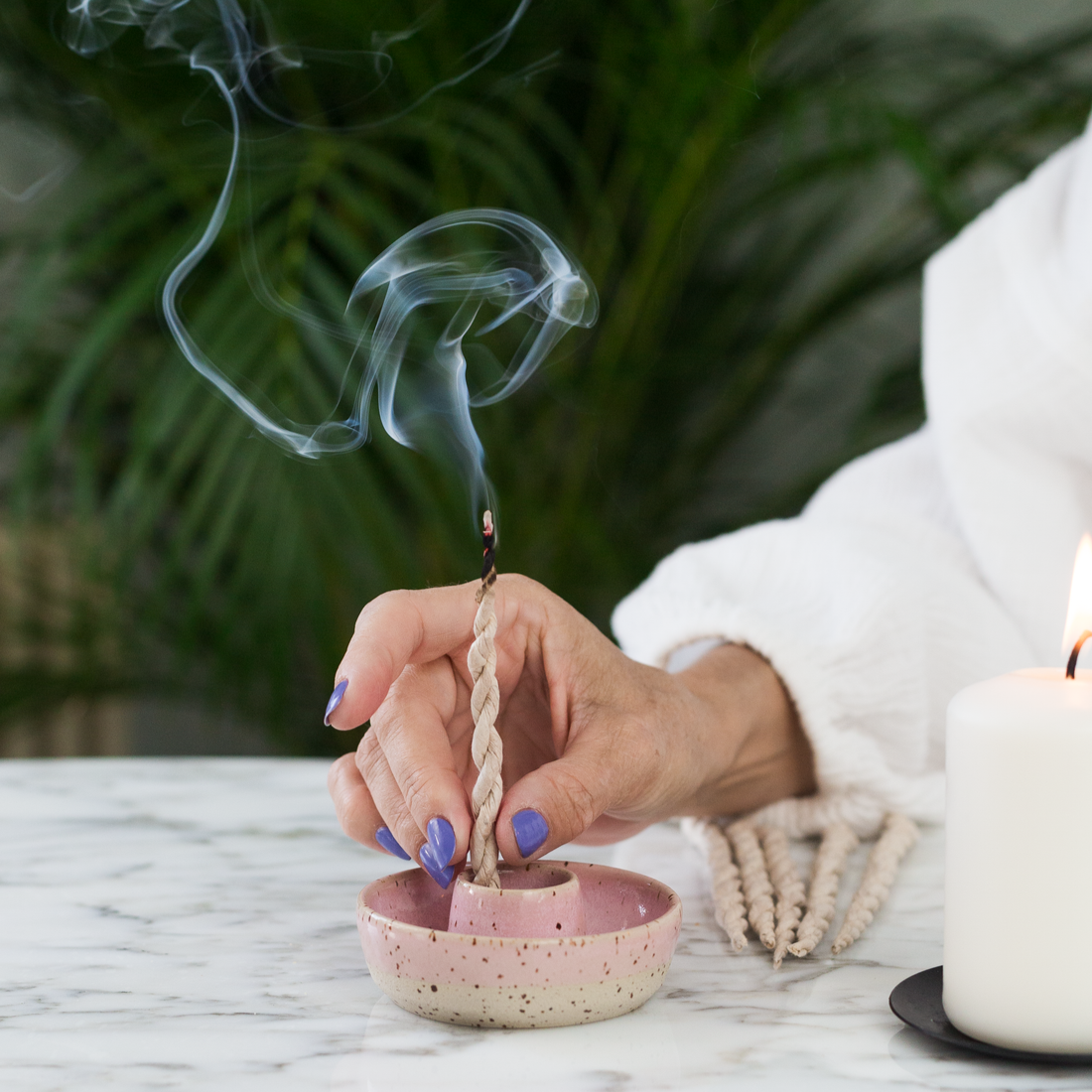 Femme tenant une cordelette incandescente d'encens tibétain dans une ambiance zen