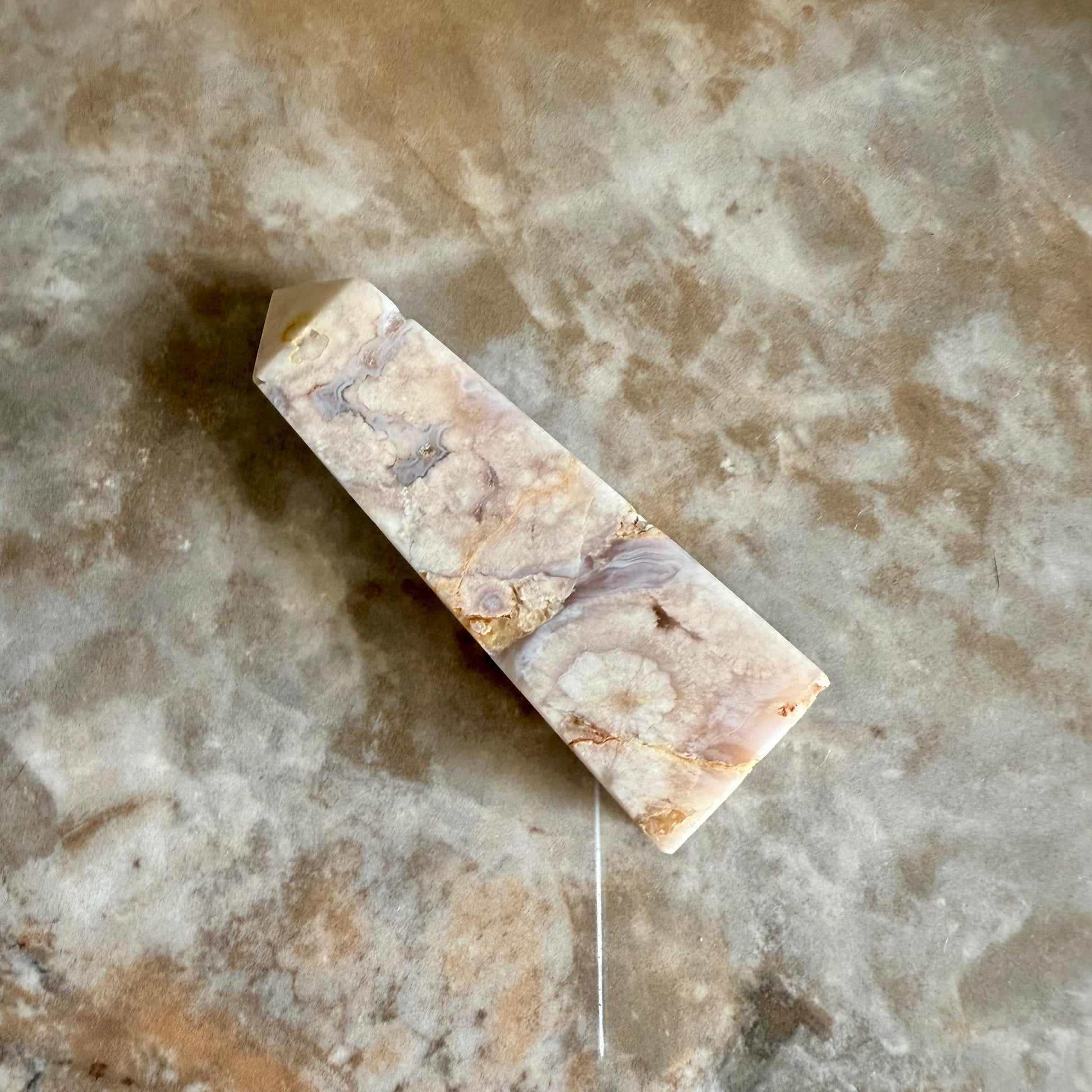 Tour d'améthyste lavande drusée posée sur une table minérale aux tons assortis, rappelant les nuances pastel et marbrées de la pierre