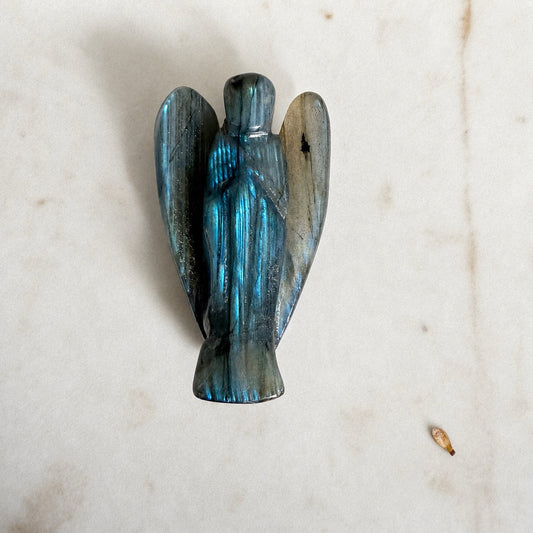Petit ange en labradorite grise aux reflets verts sur fond marbre clair