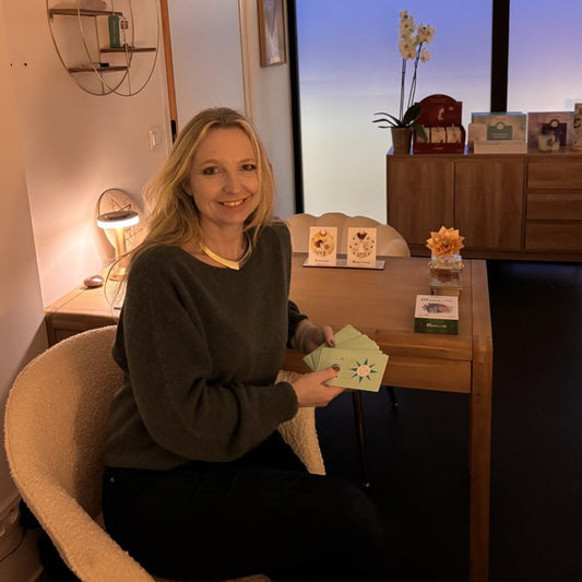 Consultation de voyance au cabinet : médium assise à son bureau, tenant un jeu d'oracles dans une ambiance chaleureuse et apaisante