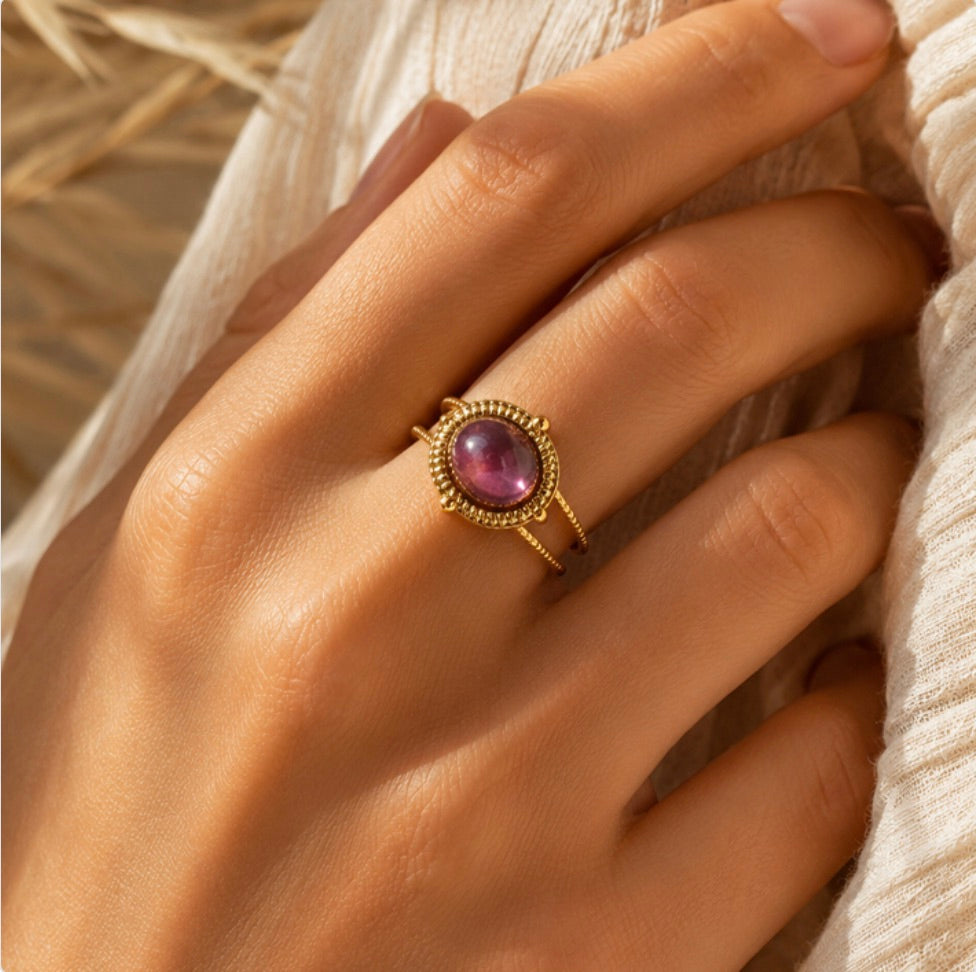 Bague dorée Sahira Essentiana ornée d’une améthyste violette portée à la main