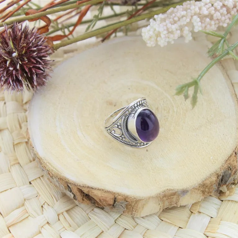 Bague en argent avec pierre en améthyste naturelle posée sur du bois