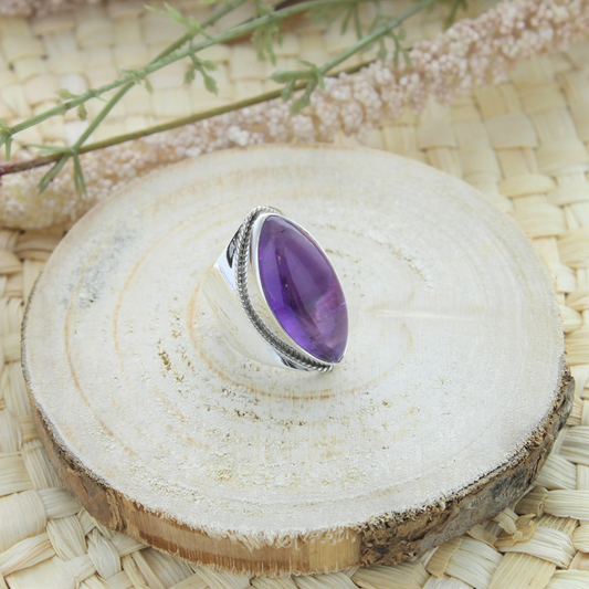 Bague en argent et améthyste en forme ovale posée sur un socle en bois
