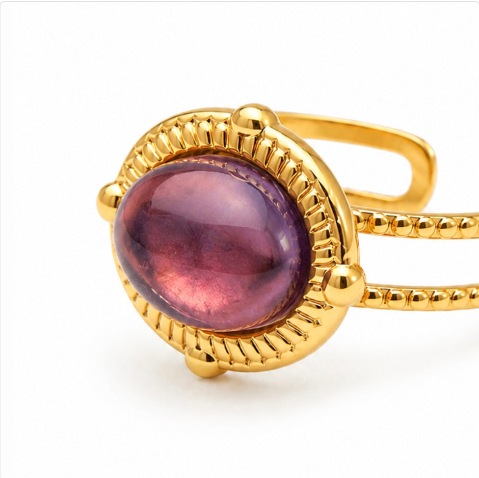 Bague dorée Sahira avec améthyste violette ovale en gros plan sur fond blanc