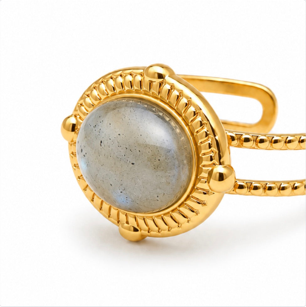 Vue de côté d’une bague Sahira dorée réglable avec pierre ovale en labradorite sur fond blanc