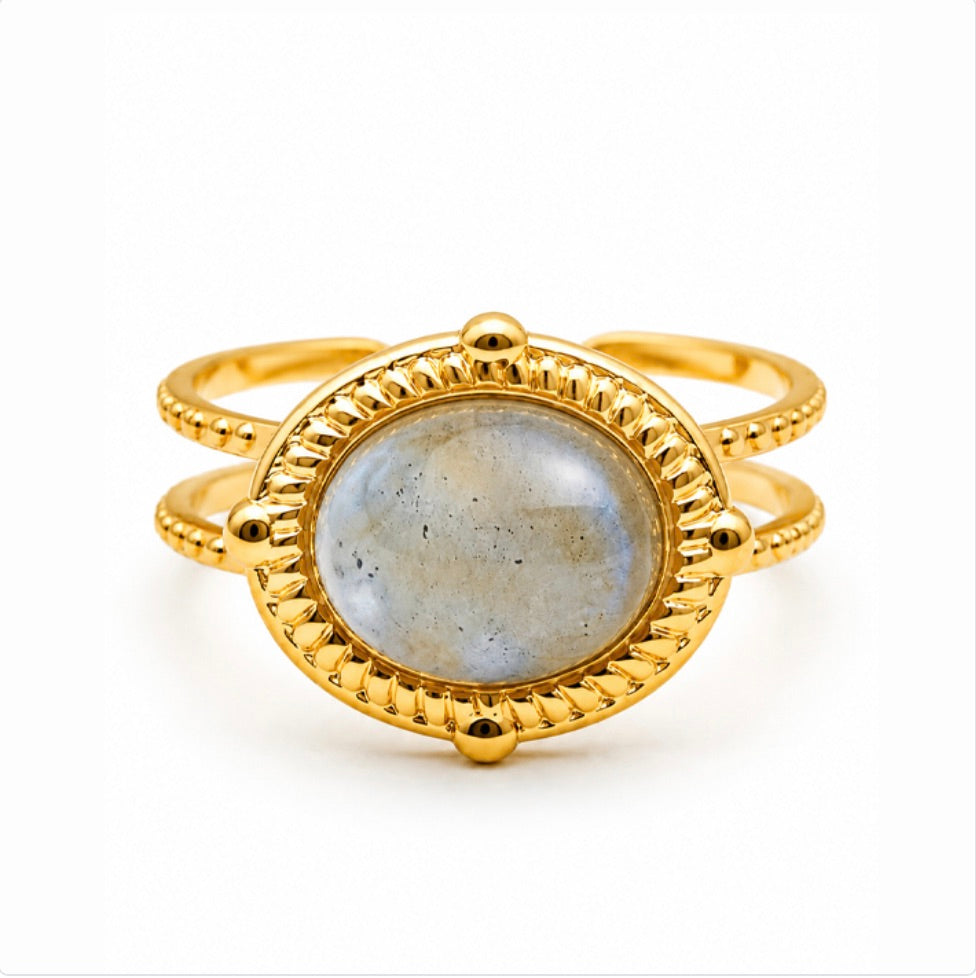 Bague Sahira dorée avec pierre ovale en labradorite et monture texturée sur fond blanc