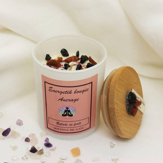 Bougie Ancrage, son pot et son couvercle en bambou posé à côté, cristaux sur le dessus, sur fond en tissu blanc crème