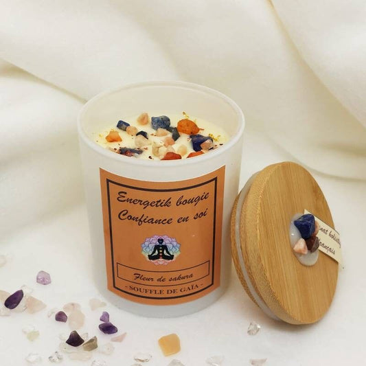 Bougie confiance en soi et son couvercle posés sur un tissu ivoire, cristaux , fleurs séchées et feuille d'or 