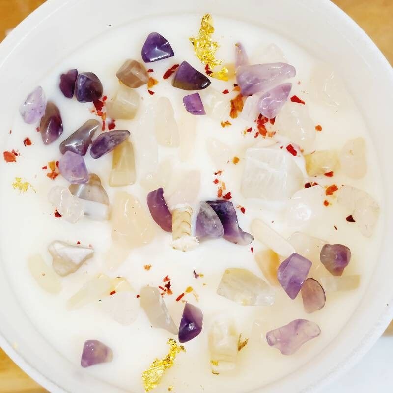 Vue de dessus de la bougie Féminin Sacré , cristaux d'améthyste, de quartz rose, de pierre de lune et de feuilles d'or et de fleurs séchées