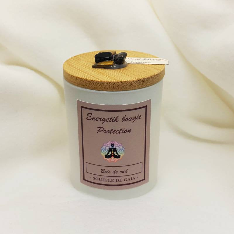 Pot de la bougie Protection Bois de Oud Souffle de Gaia avec son couvercle en bambou et ses cristaux collés, sur fond de tissu ivoire