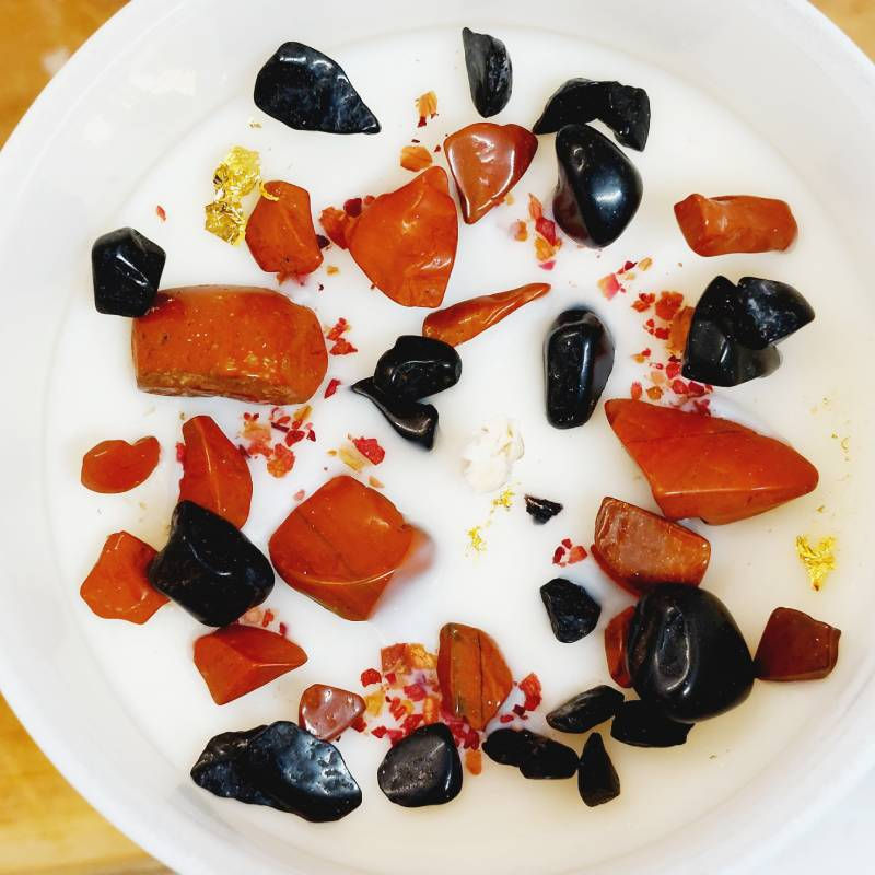 Vue de dessus d'une bougie avec ses cristaux, ses plantes et morceaux de feuille d'or