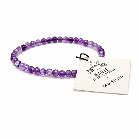 Bracelet en perles d’améthyste violettes sur fond blanc avec étiquette Magie by Jolis Baumes Medium
