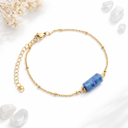 Vue d'ambiance d'un bracelet doré avec pierre centrale de lapis lazuli bleu, cristaux et fleurs séchées ivoire