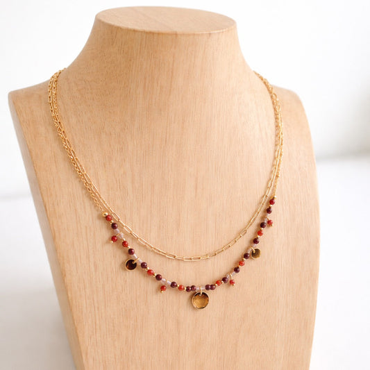 Collier double avec chaîne dorée et perles de cristal de roche et de cornalines, sur présentoir bois clair