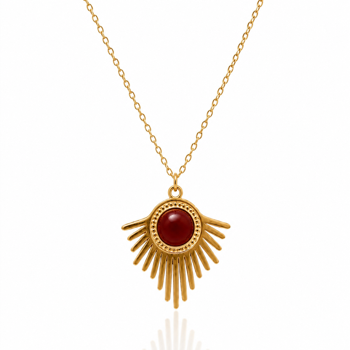 Collier solaire doré avec pierre de cornaline rouge au centre d'un pendentif en forme de soleil rayonnant sur fond blanc