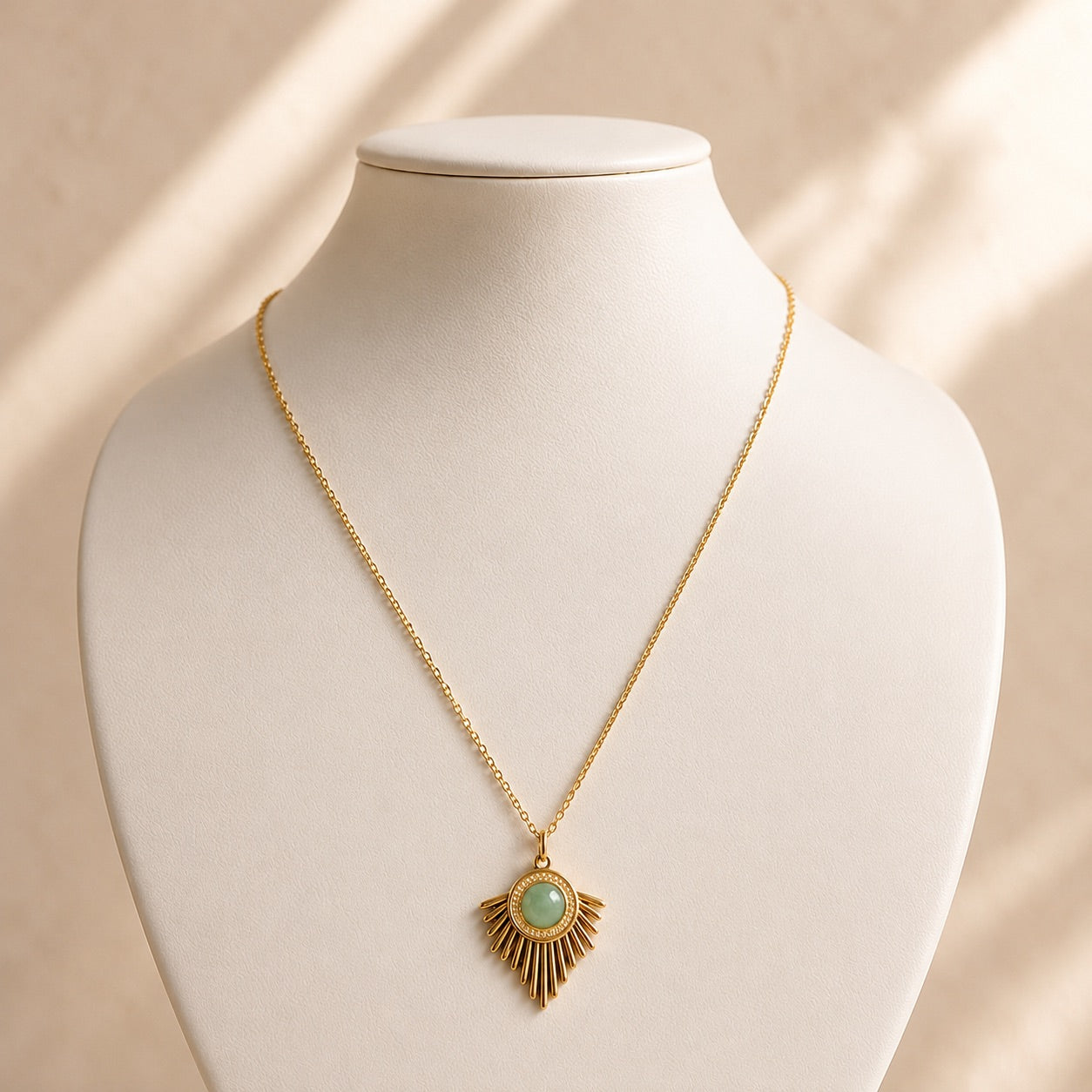 Collier doré avec pendentif solaire en acier inoxydable et pierre d'aventurine verte, présenté sur un buste blanc fond beige