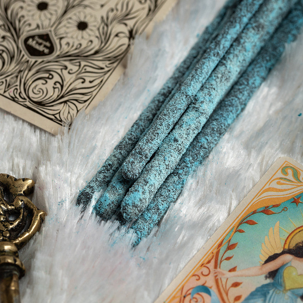 Bâtonnets d'encens Tarot Angeles Pouvoir Divin Sagrada Madre , couleur bleu turquoise, posés sur fourrure blanche avec carte de tarot et bougeoir doré
