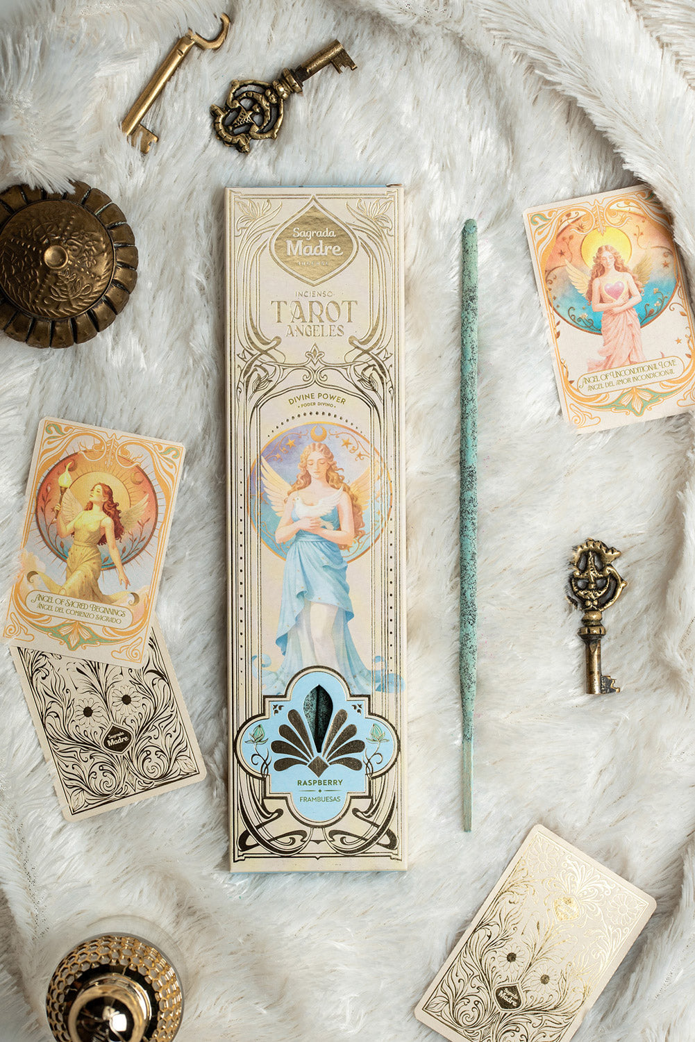 Encens Tarot Angeles Pouvoir Divin, Framboise, Sagrada Madre, boîte et bâtonnet bleu turquoise entourés de cartes de tarot et clés dorées sur fourrure blanche
