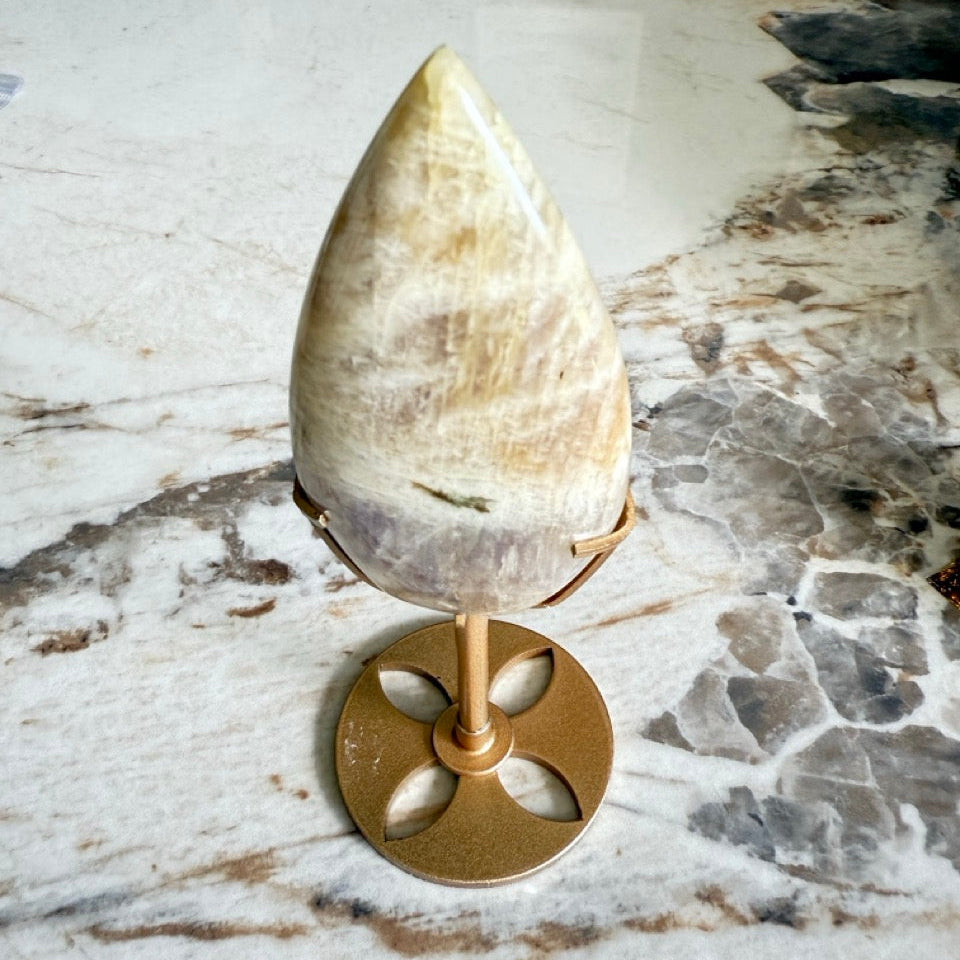 Flamme en Pierre de Lune beige et Pierre de Soleil sur socle doré, teintes beiges et dorées véinées, posée sur du marbre