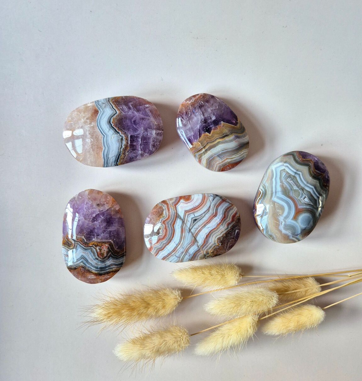 Cinq galets de pierres naturelles en agate  améthyste sur fond rosée avec herbes sèches