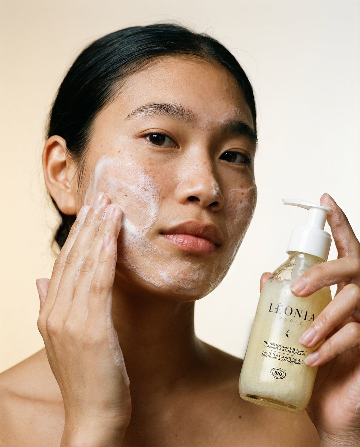 Femme de type asiatique appliquant sur son visage le gel nettoyant thé blanc apaisant et antioxydant, Léonia Paris