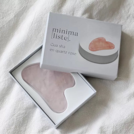 Coffret Minimaliste contenant un gua sha en quartz rose posé sur un tissu blanc