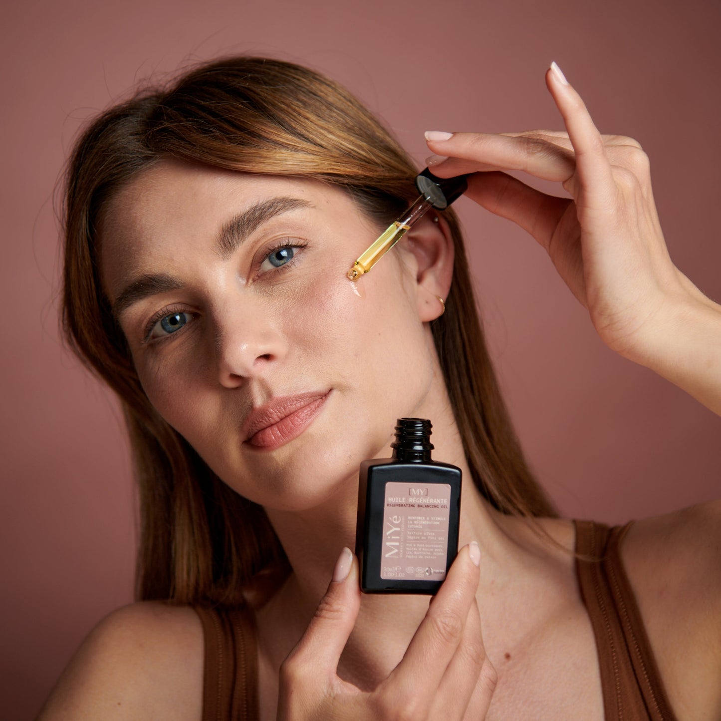 Femme appliquant sur la peau de son visage quelques gouttes de l'Huile Régénérante MiYé