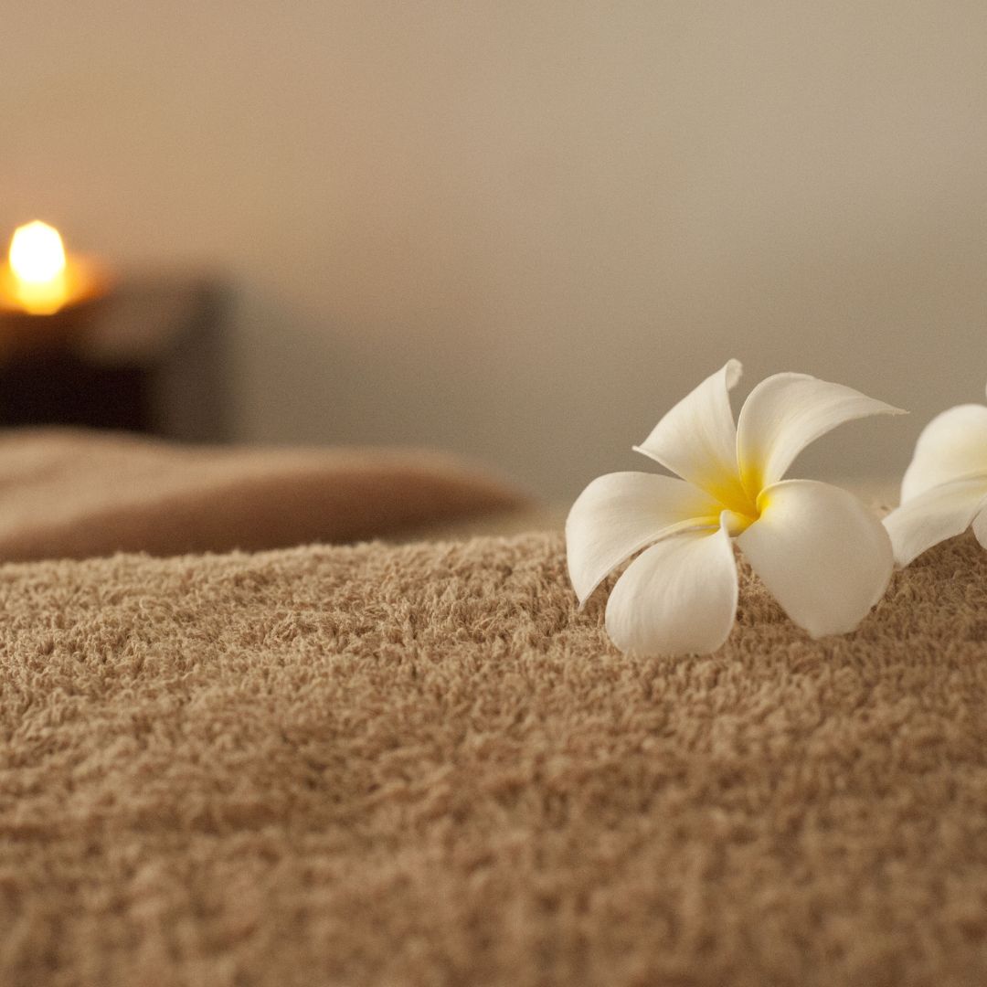 Fleurs de tiaré déposées sur une serviette éponge pour un massage corps