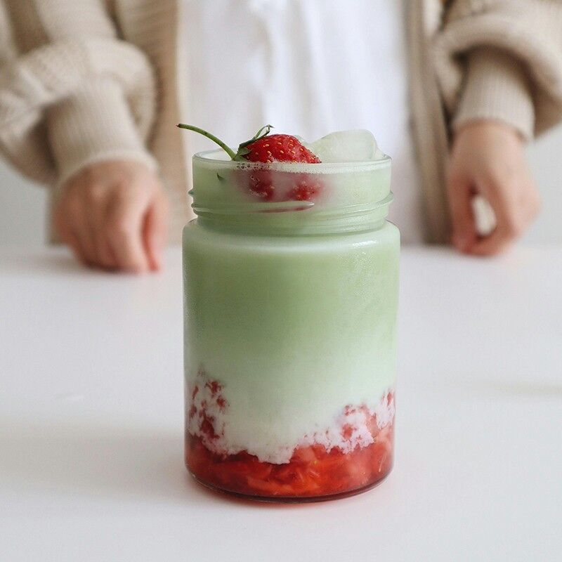 Verre de thé matcha latte avec purée de fraise au fond et fraise sur le dessus avec glaçons, recette matcha fraise Aroma Matcha
