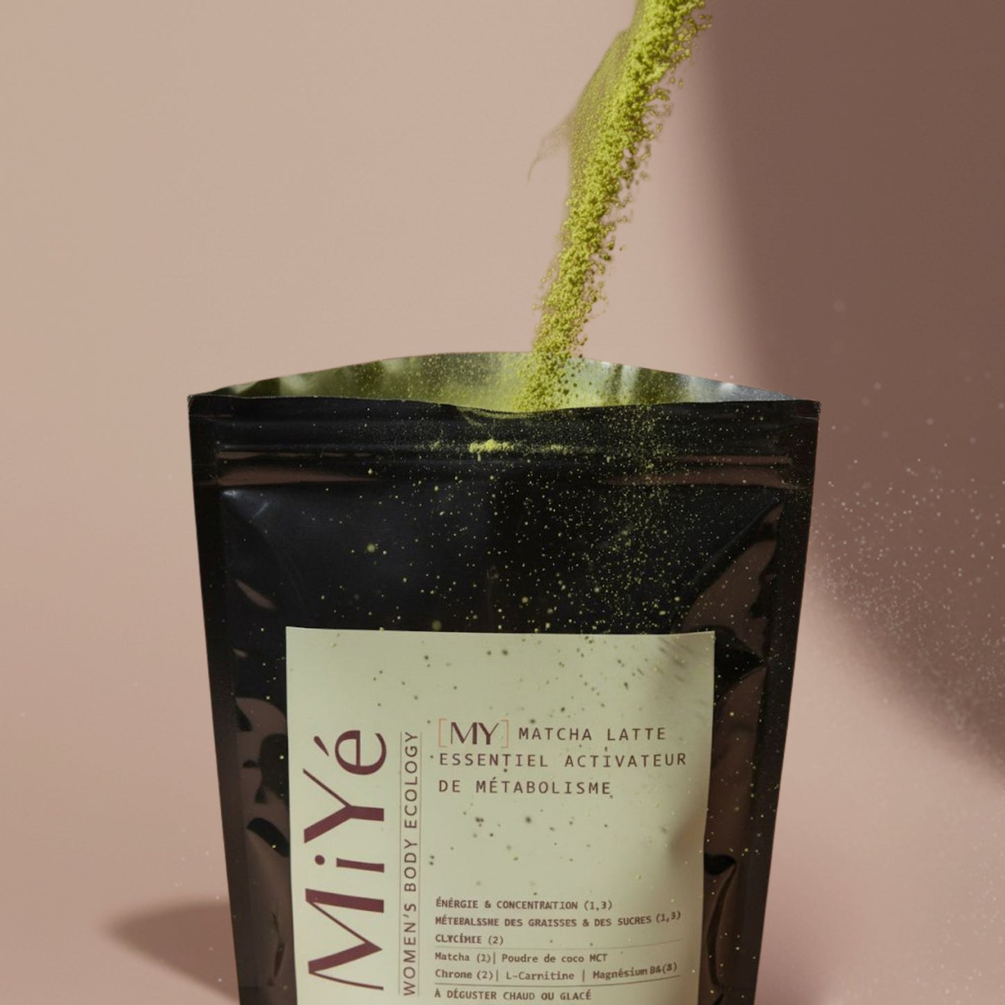 Poudre verte tombant dans un sachet noir du Matcha latte MiYé
