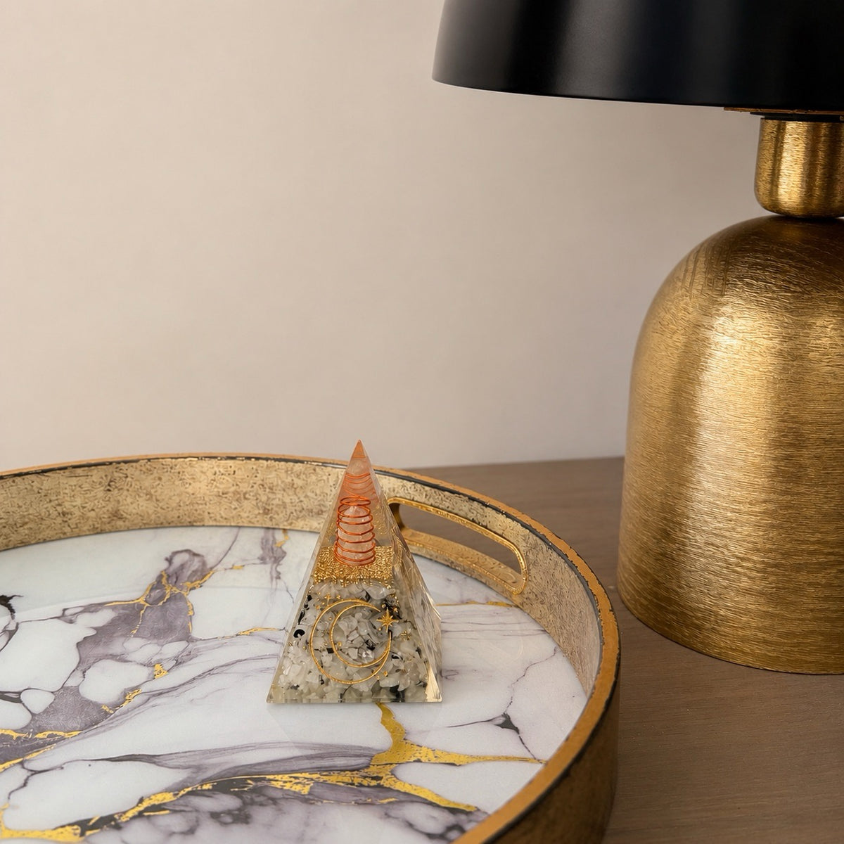 Orgonite pyramide pierre de lune posee sur plateau marbre dore ambiance chambre lumiere chaude