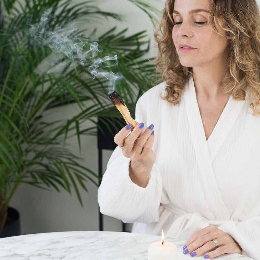 Femme tenant dans sa main un bâtonnet de Palo Santo fumant, ambiance zen