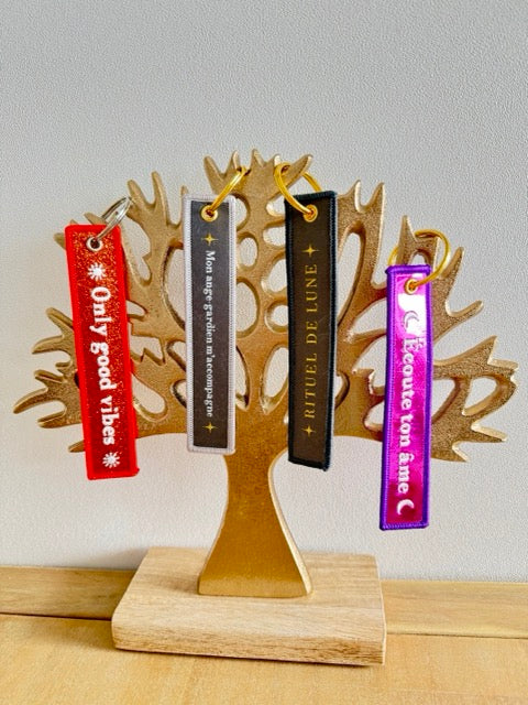Arbre de vie doré sur socle en bois claire avec 4 porte clés rubans avec messages, rouge : only good vibes, gris : mon ange gardien m'accompagne, anthracite : rituel de lune, rose : écoute ton âme