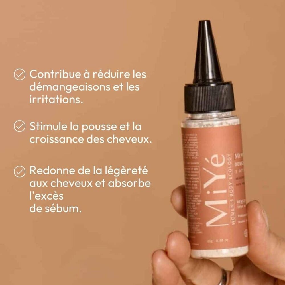 Main tenant un flacon de poudre cheveux densifiante MiYé, liste de ses bienfaits