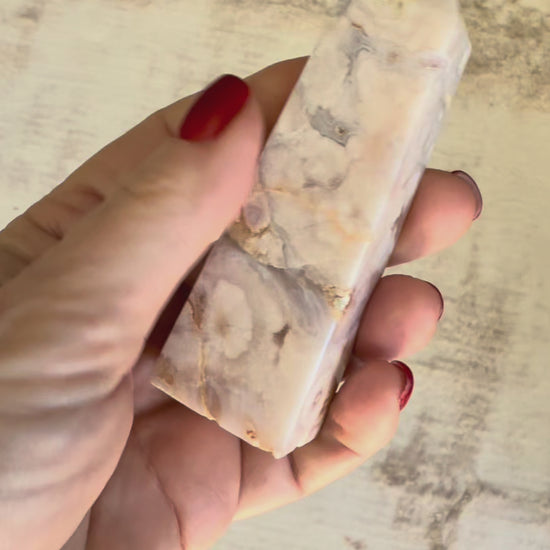 Vidéo d'une tour d'améthyste lavande drusée tenue dans la main, tournée lentement pour révéler ses nuances pastel