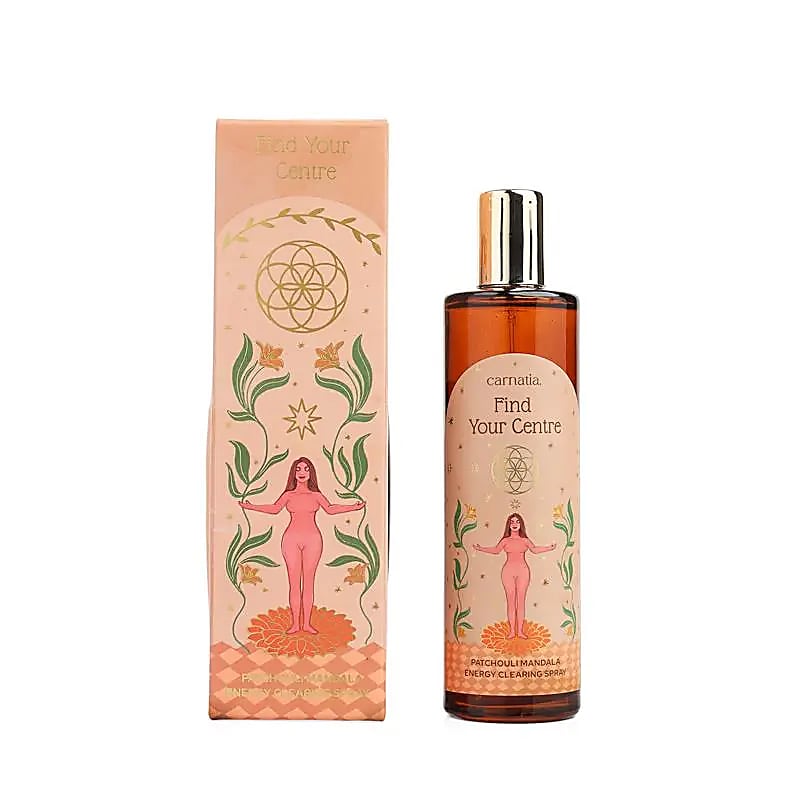 Flacon vaporisateur ambré Carnatia Find Your Centre à côté de son coffret rose orné d'une fleur de vie dorée, de motifs floraux et d'une illustration de femme les bras ouverts, spray d'ambiance patchouli mandala.