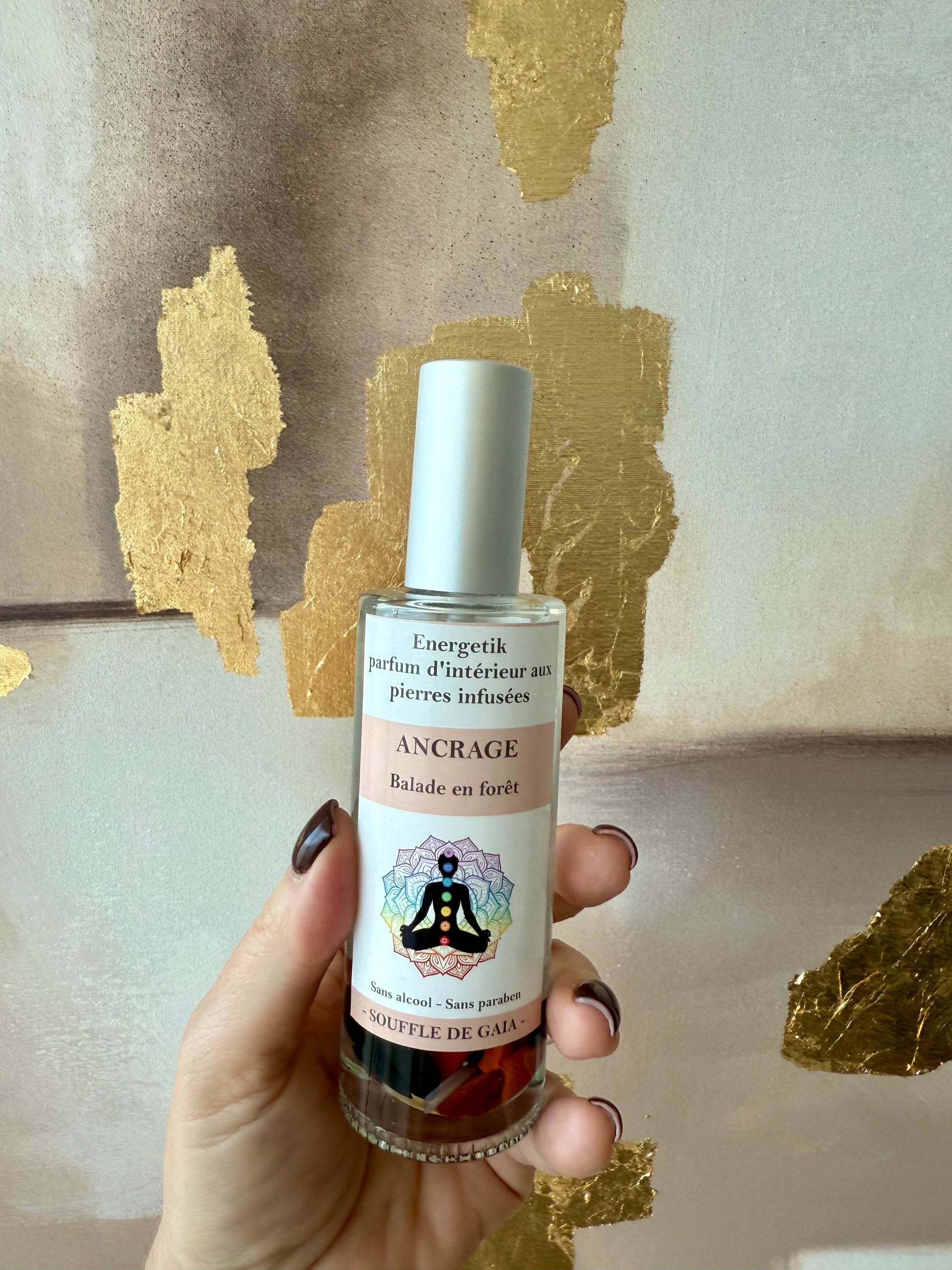 Main de femme tenant un flacon de parfum d'intérieur aux pierres infusées, à la senteur balade en forêt et à l'intention d'ancrage
