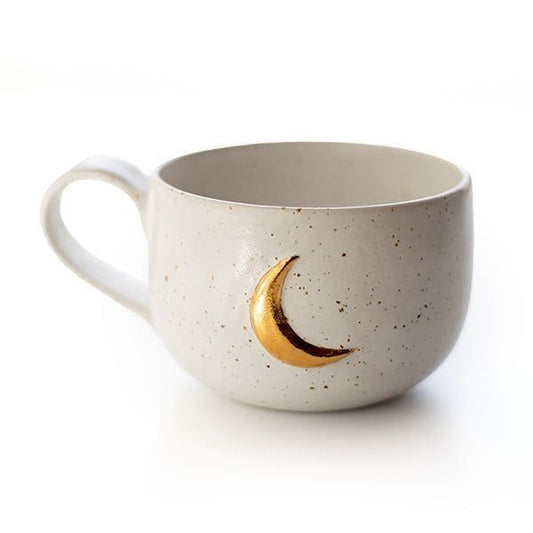 Tasse en grès beige moucheté avec lune dorée, posée sur fond clair, grande contenance