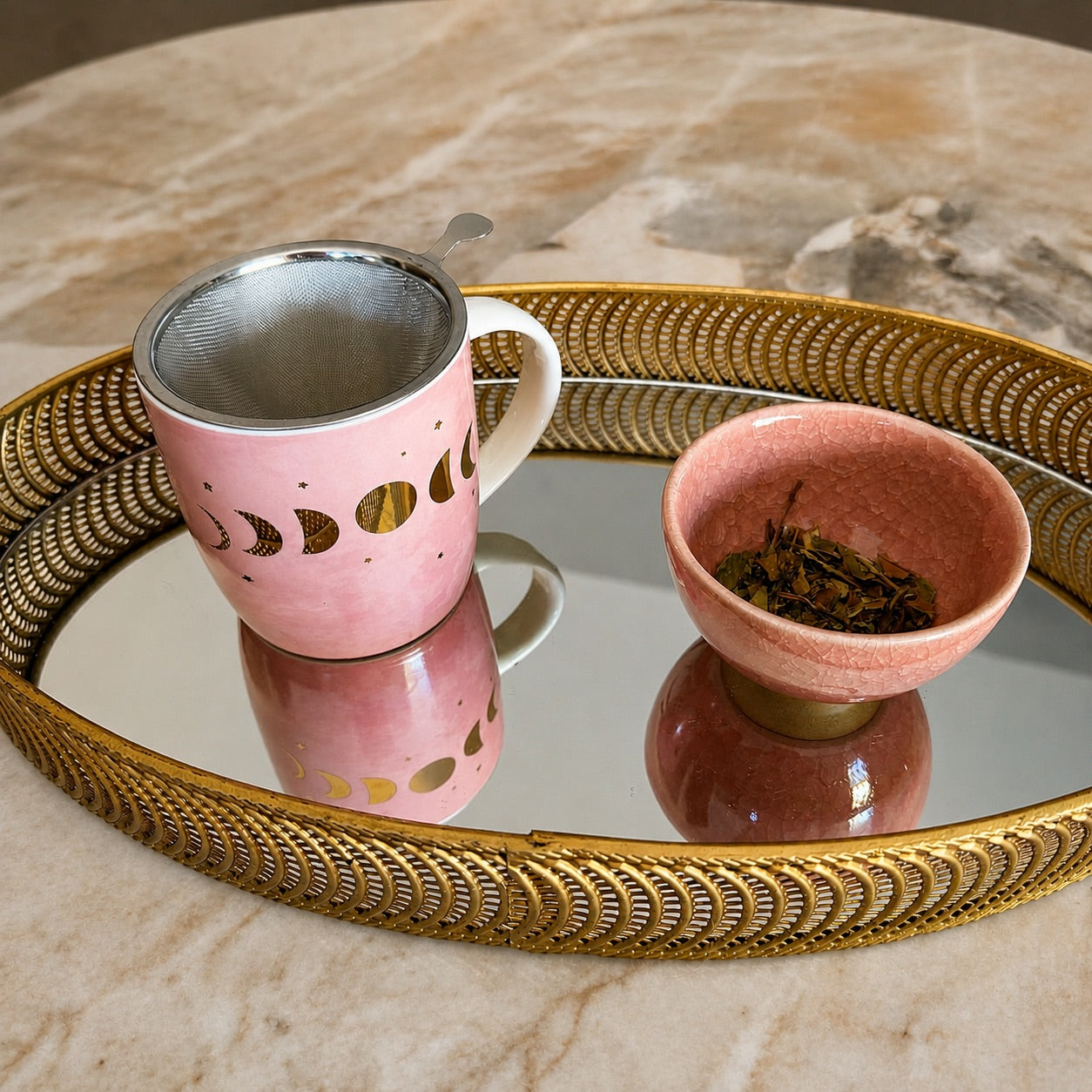 Tasse phases de lune rose avec infuseur inox sur plateau miroir doré avec bol de thé
