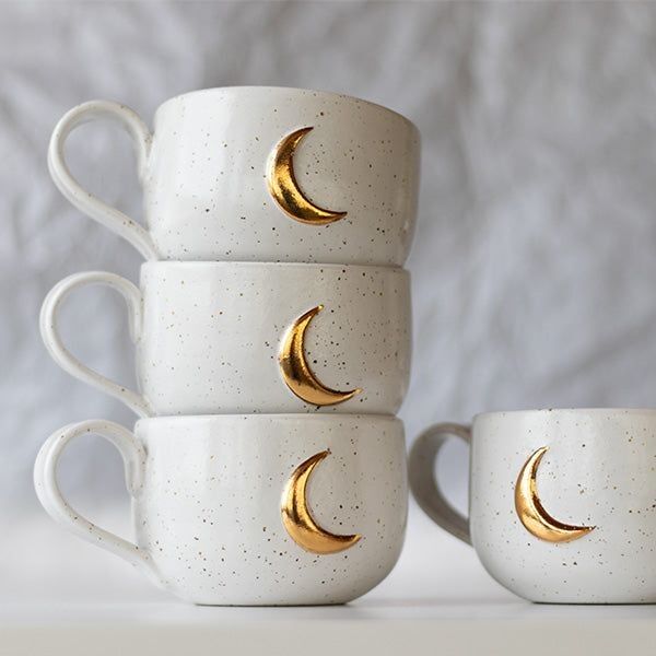 3 tasses en grès beige moucheté avec lune doré empilées et une tasse posée