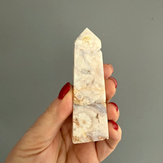 Tour d'améthyste lavande druzée tenue dans la main, montrant ses reflets pastel