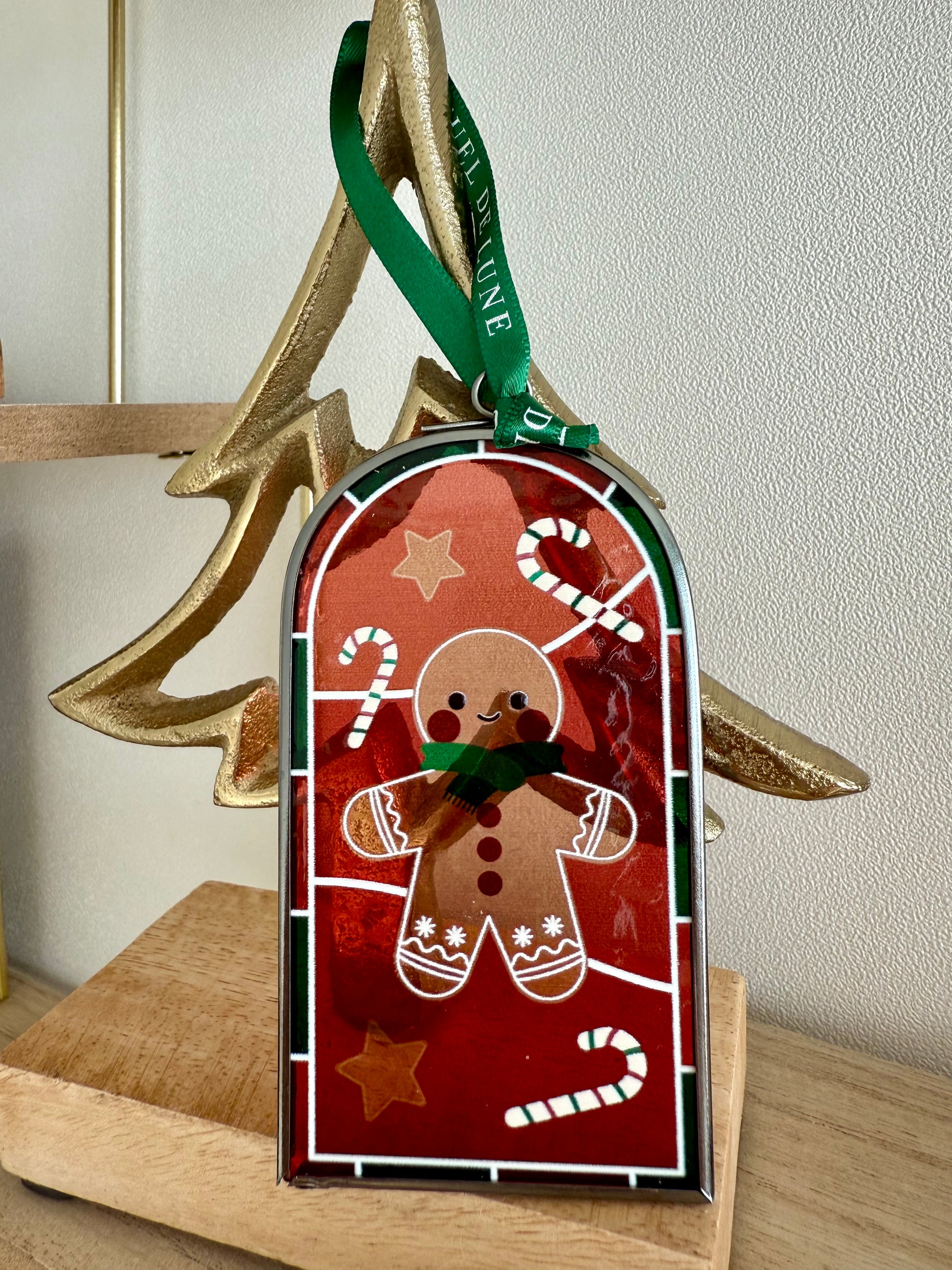 Mini vitrail bonhomme pain d'épice accroché avec un ruban vert Rituel de lune sur un sapin doré, socle bois